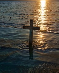 Christian cross in the water with sunset