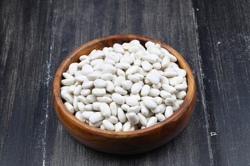 white kidney bean in wooden bowl isolated on wooden background. Top view. Flat lay