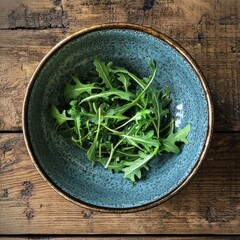 Arugula and ceramic bowl on table.