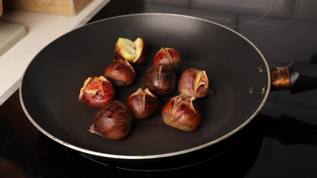 Opening pan lid while roasting chestnuts &mdash; autumn comfort food. Hot chestnuts with a warm, seasonal aroma. Cozy homemade fall tradition.