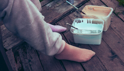 Preparing paint for renovation work, women's legs and containers with paint on a wooden floor