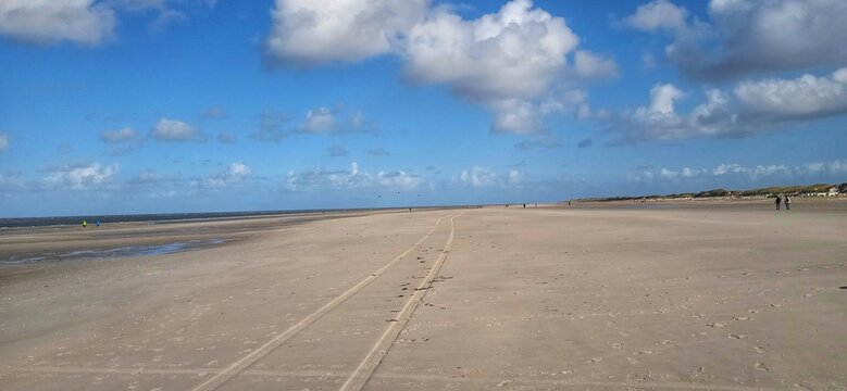 Strandblick unter blauem Himmel mit Spuren im Sand 
