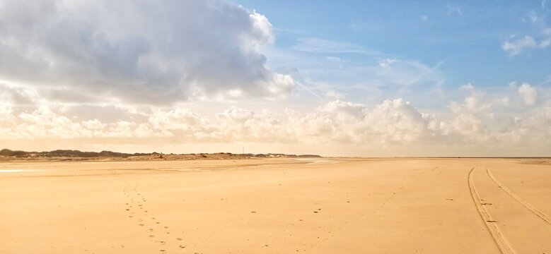 Weiter Strand mit gelben Sand und Wolken 