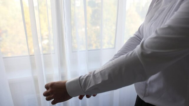 the groom is buttoning the cufflinks on his shirt in the room