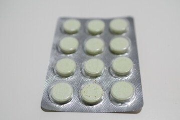 A pack of twelve natural, light green, plant-based tablets. Photographed on a white background packaged.