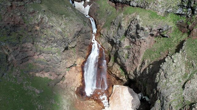 Tripod aerial shot of Gagharot waterfall on the Mount Aragats slope from sun to shadow. Armenia.