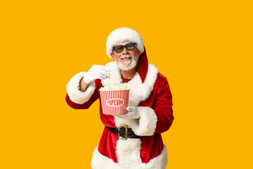 Santa Claus in 3D glasses with bucket of tasty popcorn on yellow background