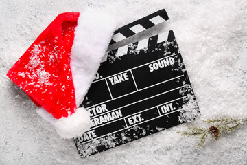 Movie clapper with Santa hat and decorative snow on grunge background