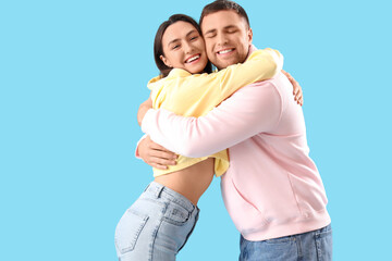 Fototapeta premium Happy young couple hugging on blue background