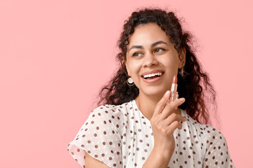 Beautiful young African-American woman with lipstick on pink background