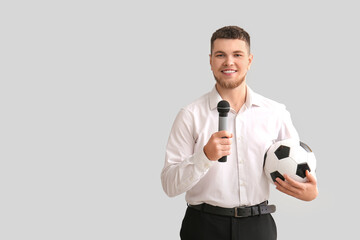 Male reporter with microphone and soccer ball on grey background