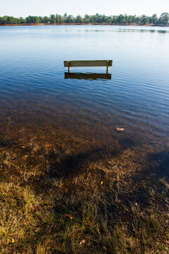 A park bench halfway submerged in water in a flooded lake in Florida