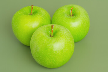 Three ripe green apples on a green background. Apples, fruits.