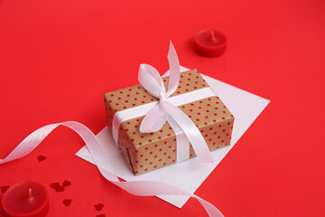 Gift box with envelope and candles on red background. Valentine's Day celebration