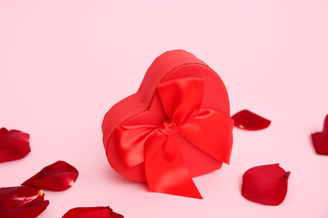 Gift box and rose petals on pink background. Valentine's Day celebration