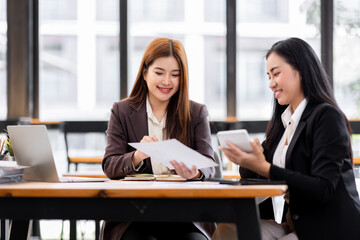 Business financing accounting banking concept. Two asian Business doing finances and calculate on desk about cost at workplace. Business working on desk with using calculator, finance accounting.
