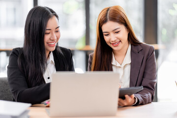 Business financing accounting banking concept. Two asian Business doing finances and calculate on desk about cost at workplace. Business working on desk with using calculator, finance accounting.
