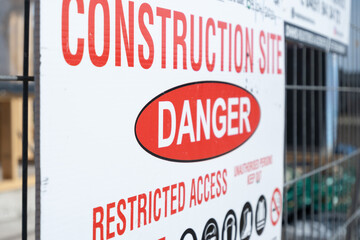 a sign at a construction site with restricted access. The text that reads "CONSTRUCTION SITE" and "DANGER" to warn the public that the area an active construction zone with potential safety hazards