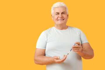 Diabetic mature man using lancet pen on yellow background