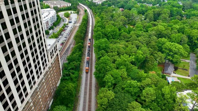Amazing 4k drone footage of moving train in Buckhead Atlanta Georgia.  Smooth cinematic aerial drone footage of moving train and lush green trees near modern architecture. 