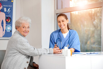 Diabetic senior woman with doctor using lancet pen at table in clinic