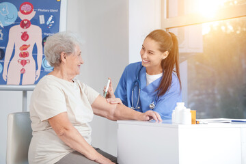 Diabetic senior woman with doctor using lancet pen in clinic
