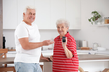Diabetic senior couple with glucometer in kitchen
