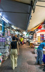 Obraz premium A woman walks through the market in Sampeng Lane, Chinatown, Bangkok, Thailand - blurred background
