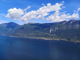 Breathtaking View of Lake Garda Surrounded by Majestic Mountains and Verdant Cliffs on a Clear Day in Italy