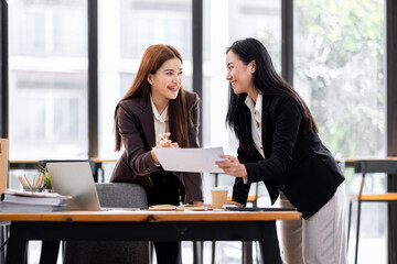 Two asian business women discuss data on document graph report. Meeting and Talking.advising each other in office,