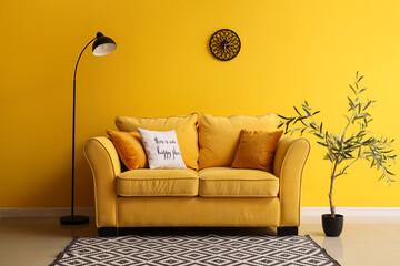 Comfortable sofa, floor lamp and decorative olive tree in interior of living room