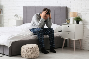 Depressed young man sitting in bedroom