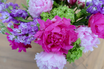 Obraz premium A vivid floral arrangement featuring fuchsia peonies, pale pink blossoms, purple blooms, and fresh green accents, exuding elegance and the beauty of nature’s vibrant colors.