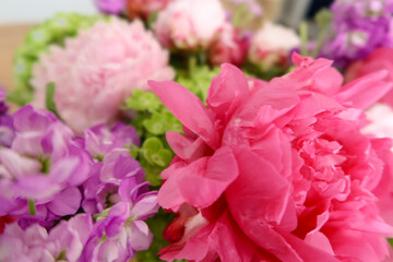 A vivid arrangement showcasing pink and purple flowers, accented with fresh green leaves, highlighting the delicate textures and vibrant colors in a softly blurred background.