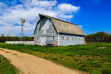 Obraz premium A large, old-fashioned barn sits in a field with a dirt road leading to it