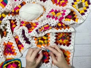 Crocheting granny square blanket process and woman's hands hobby handmade handiwork clews and hook cozy winter autumn fall photo