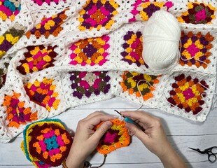 Crocheting granny square blanket process and woman's hands hobby handmade handiwork clews and hook cozy winter autumn fall photo