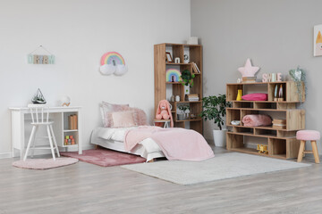 Interior of light children's room with bed, shelf units and table