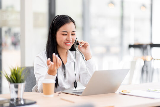 Smiling friendly asian female call-center agent with headset working on support call center agent  hotline in the office