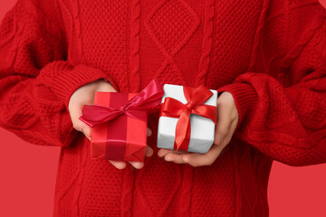Young woman holding gift boxes on red background. Valentine's Day celebration