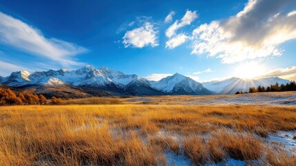 Obraz premium Breathtaking autumn landscape with snow capped mountain peaks golden meadows and a serene lake reflecting the dramatic sky at sunset Scenic and peaceful natural environment in the wilderness