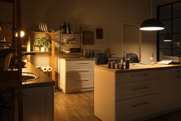 Interior of dark kitchen with counters, shelves and glowing lamps at night