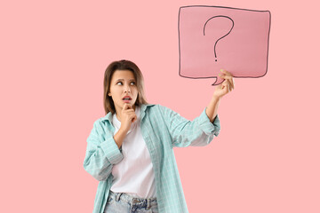 Thoughtful young woman holding speech bubble with question mark on pink background