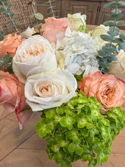 A vibrant close-up of peach-colored roses with ruffled petals in full bloom, set against a softly blurred home interior, creating a warm and elegant floral centerpiece.