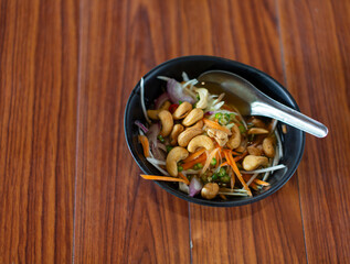 Cashew nuts in black cup placed on wooden table with copy space for use