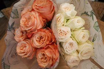 Two stunning bouquets featuring vibrant orange and soft white roses, wrapped in delicate floral paper, perfect for special occasions or thoughtful gifts.