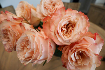 A vibrant bouquet of peach-orange roses with intricate, ruffled petals, arranged in a loose, natural style, creating a soft and romantic display perfect for any occasion.