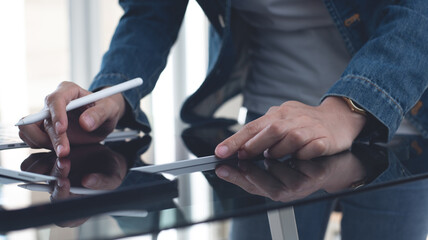 Close up, casual business woman using stylus pen working on digital tablet with laptop computer on table at home office. Graphic designer creates art work via mobile app, freelance at work