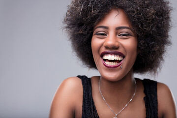 Young woman with afro hair smiling and showing teeth