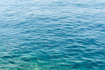 Calm turquoise water surface with soft ripples and natural sunlight reflections on a clear day. Concept of tranquility, nature, and serene aquatic textures.